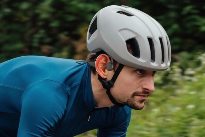 Road cyclist wearing a helmet and bone conduction headphones with open-ear for cycling safety